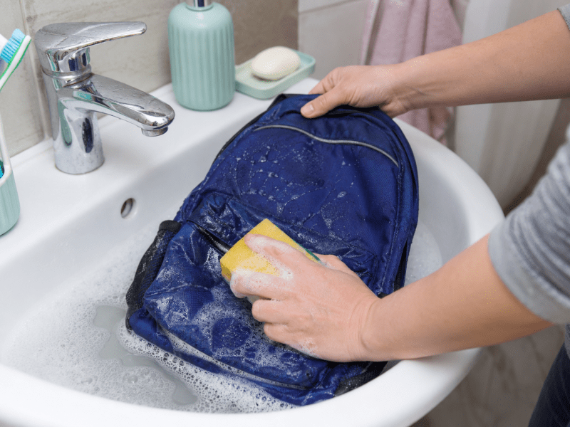 Curățarea manuală a unui ghiozdan cu burete moale și apă cu detergent.
