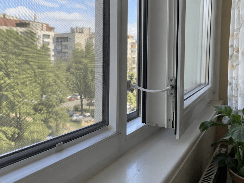 Plasă de insecte și limitator de siguranță montat pe o fereastră PVC