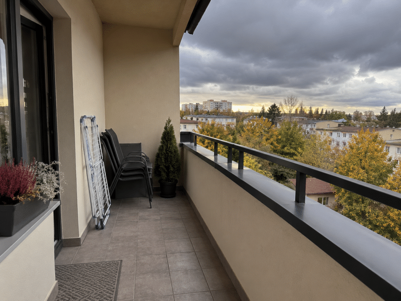 Uscător de rufe pliat și scaune de balcon așezate lângă perete înainte de vreme rea